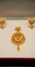 Gold pendant and earrings set on a white background