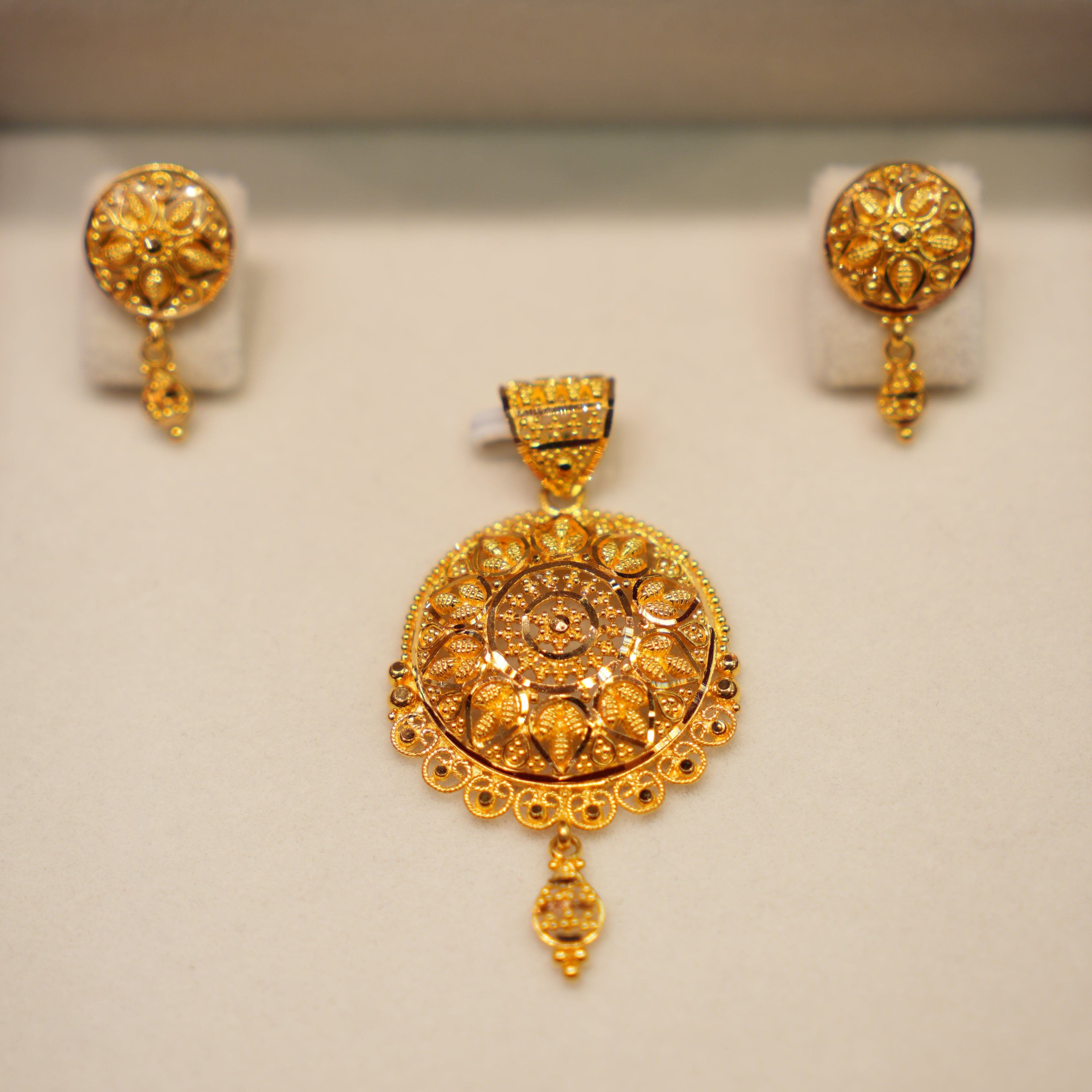 Gold pendant and earrings set on a white background