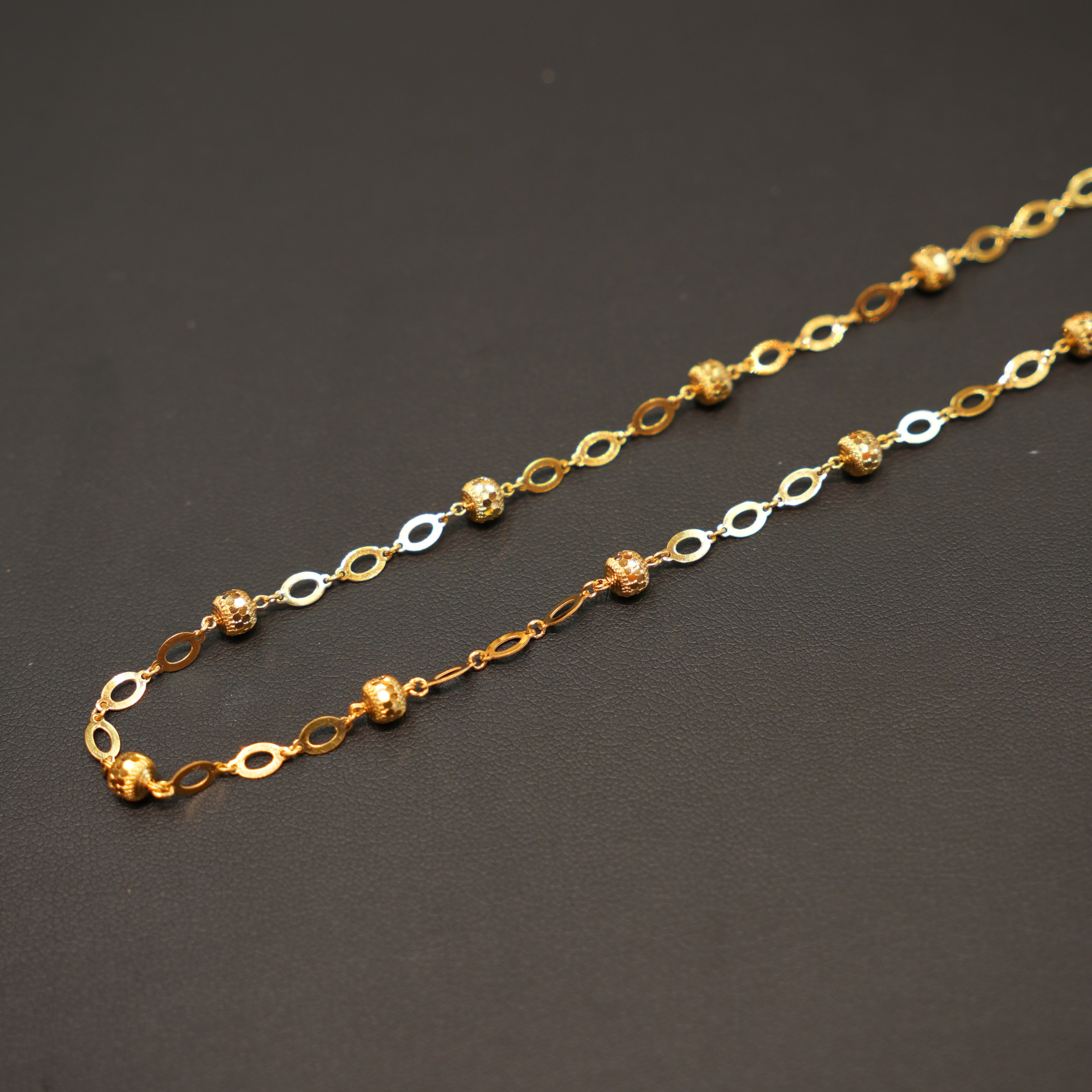 Gold and silver chain necklace on a dark gray background