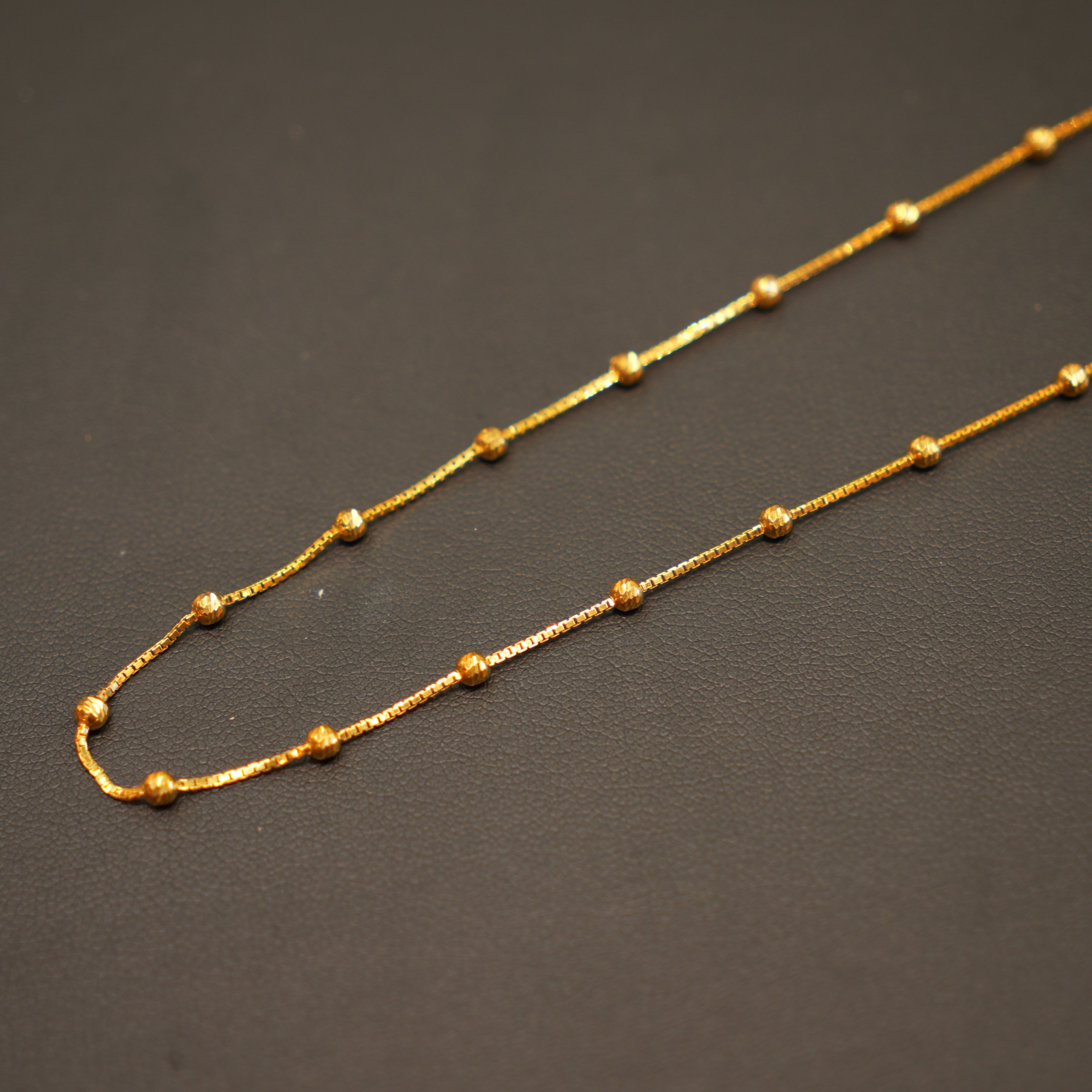 Gold chain necklace on a dark gray background