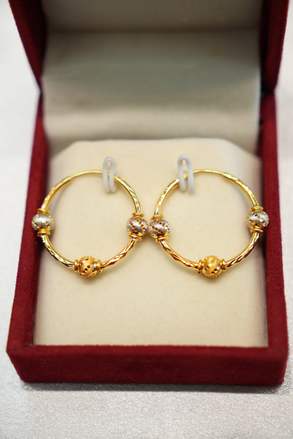 Gold hoop earrings with small stones in a red jewelry box.