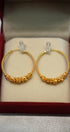 Gold hoop earrings with intricate designs in a red box.