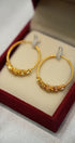 Gold hoop earrings on a red cushioned stand