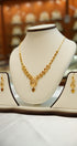 Gold necklace and earrings on a mannequin bust with a blurred jewelry store background.
