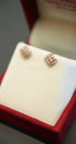 Pair of diamond earrings on a white cushion in a red jewelry box.