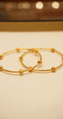 Two gold hoop earrings on a beige background