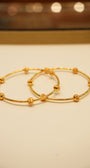 Two gold hoop earrings on a beige background