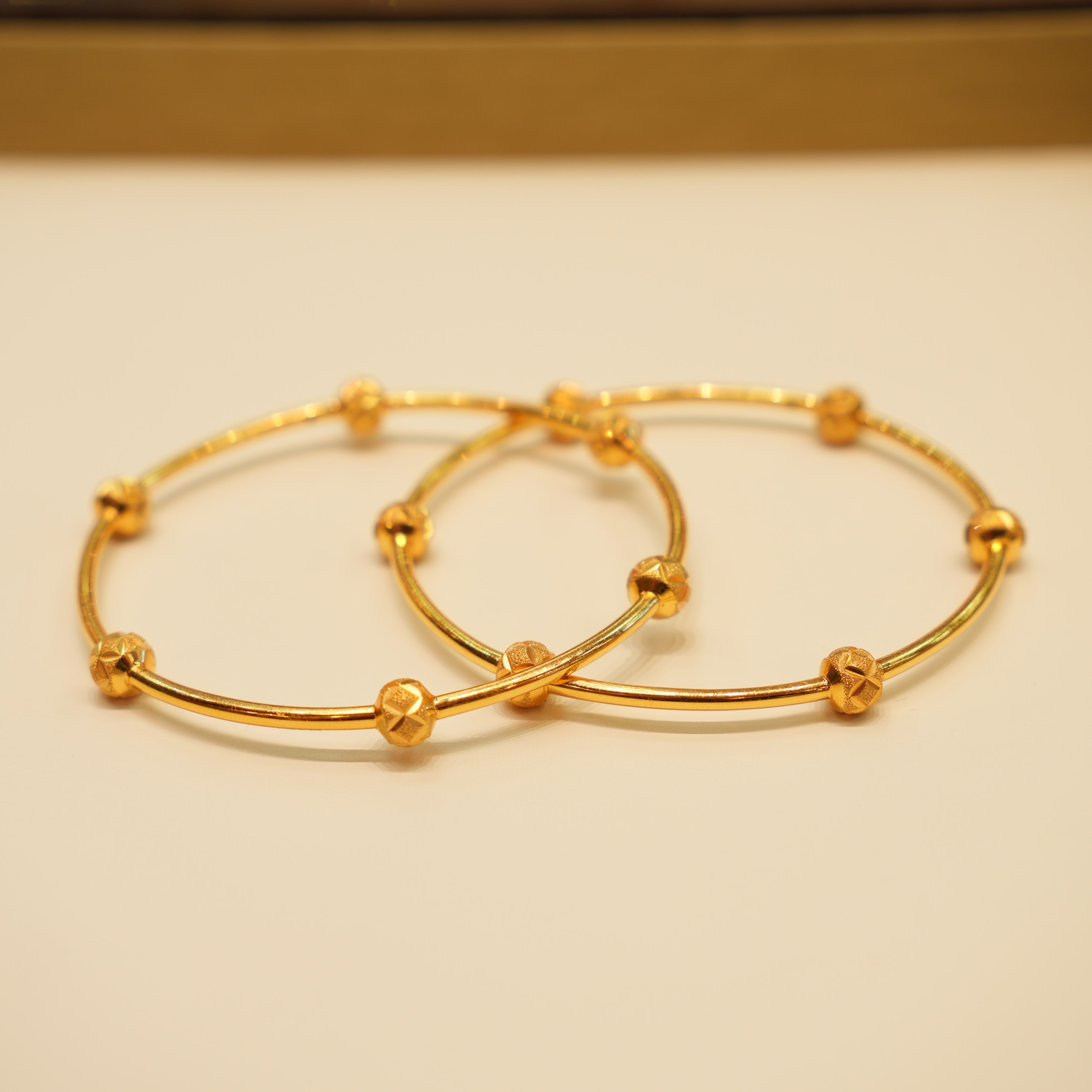Two gold hoop earrings on a beige background