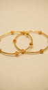 Two gold hoop earrings on a beige background