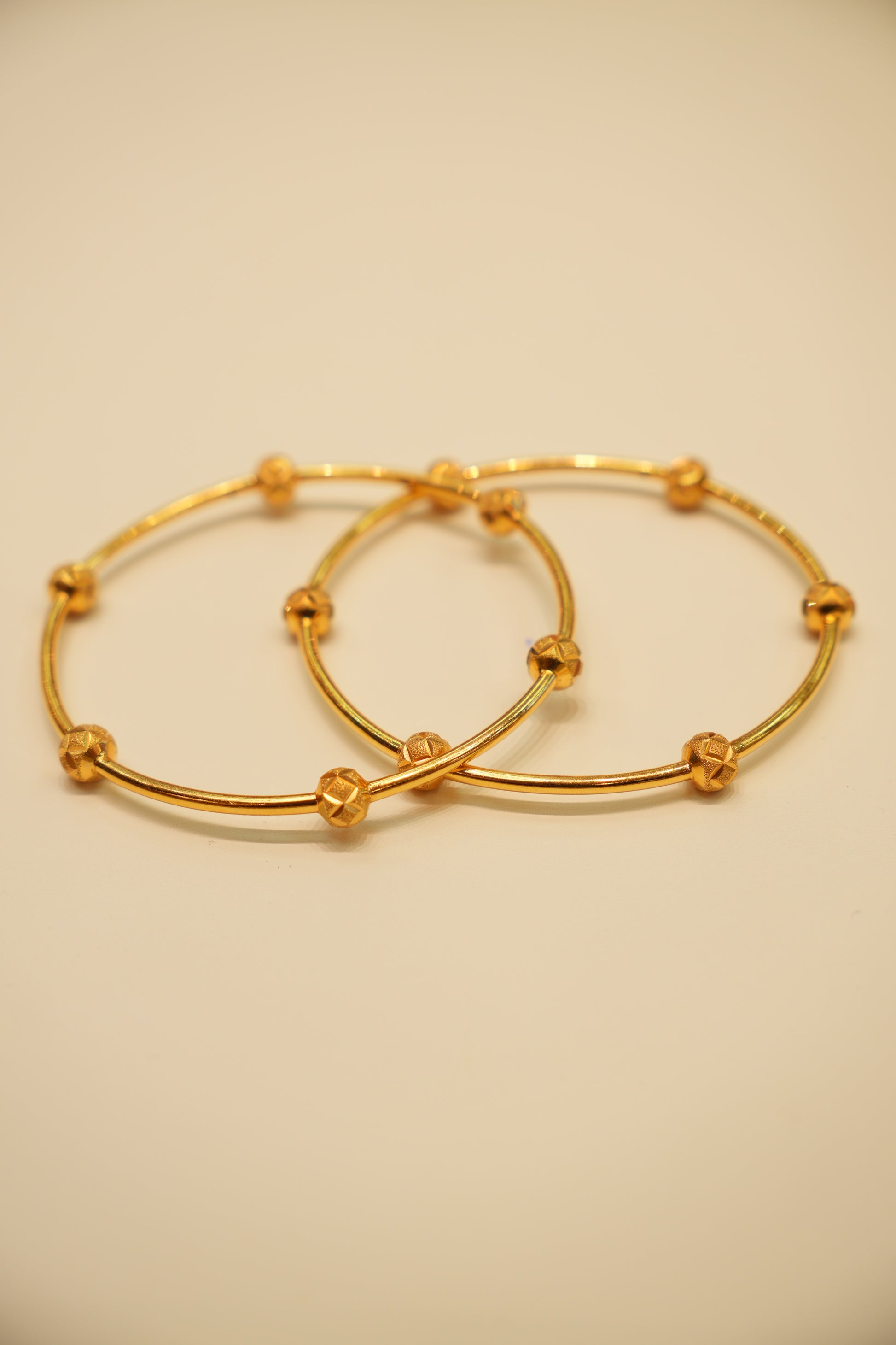 Two gold hoop earrings on a beige background