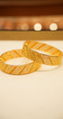 Two gold bangles on a light background