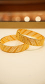 Two gold bangles on a light background