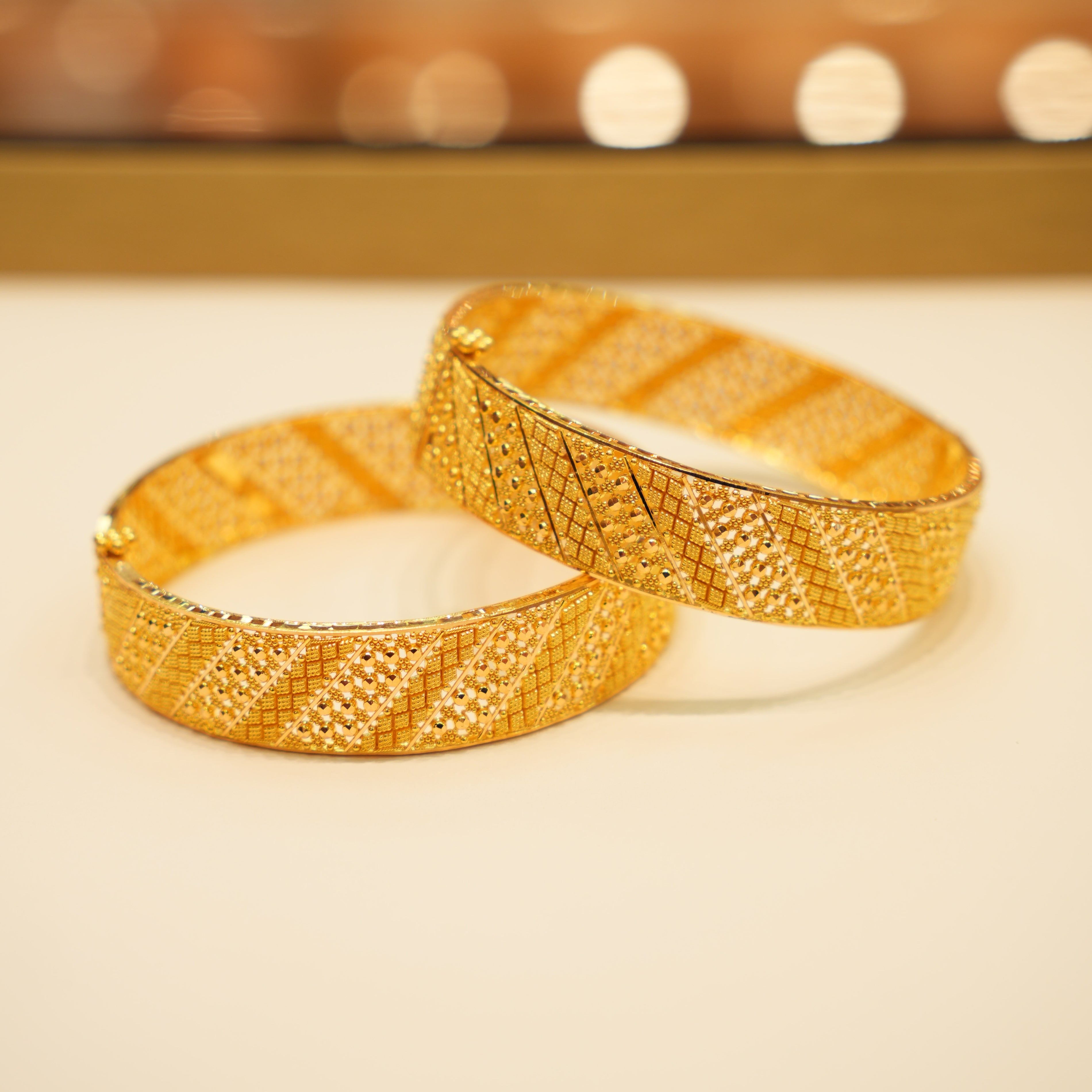 Two gold bangles on a light background