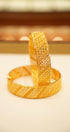 Gold bracelet with textured design on a light background