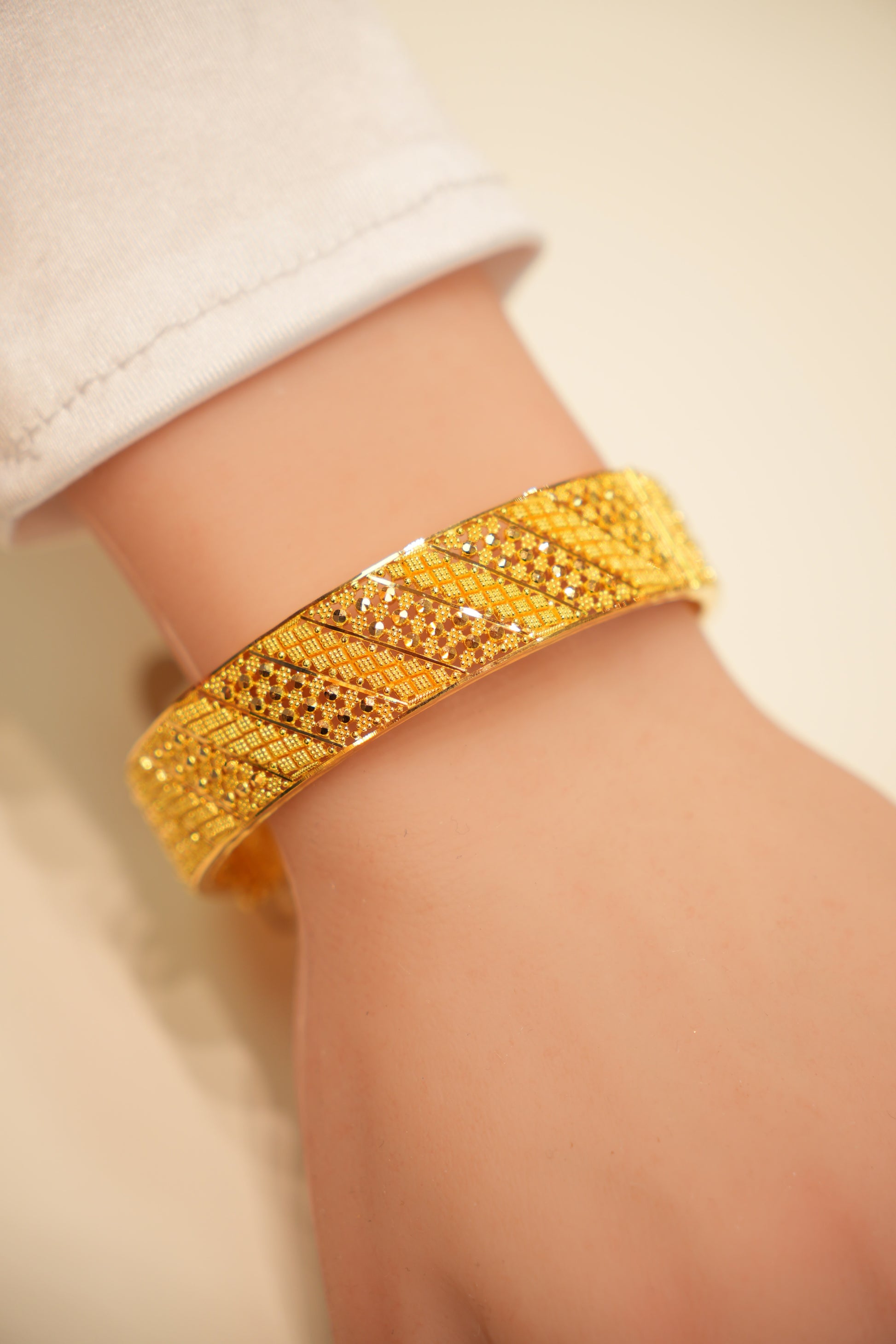 Gold bracelet on a person's wrist with a neutral background