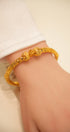 Gold bracelet on a wrist with a plain background