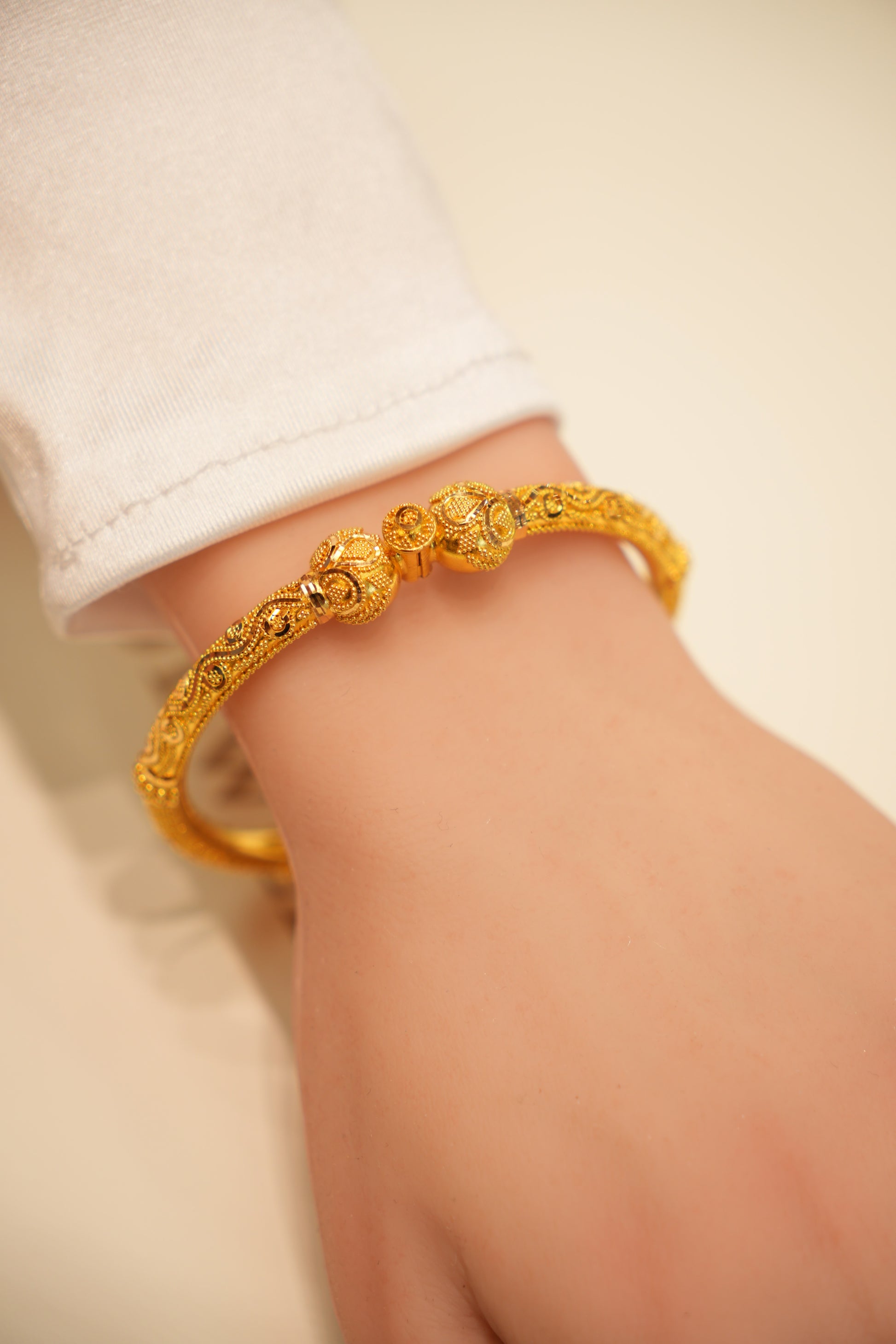 Gold bracelet on a wrist with a plain background