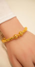 Gold bracelet on a person's wrist with a plain background