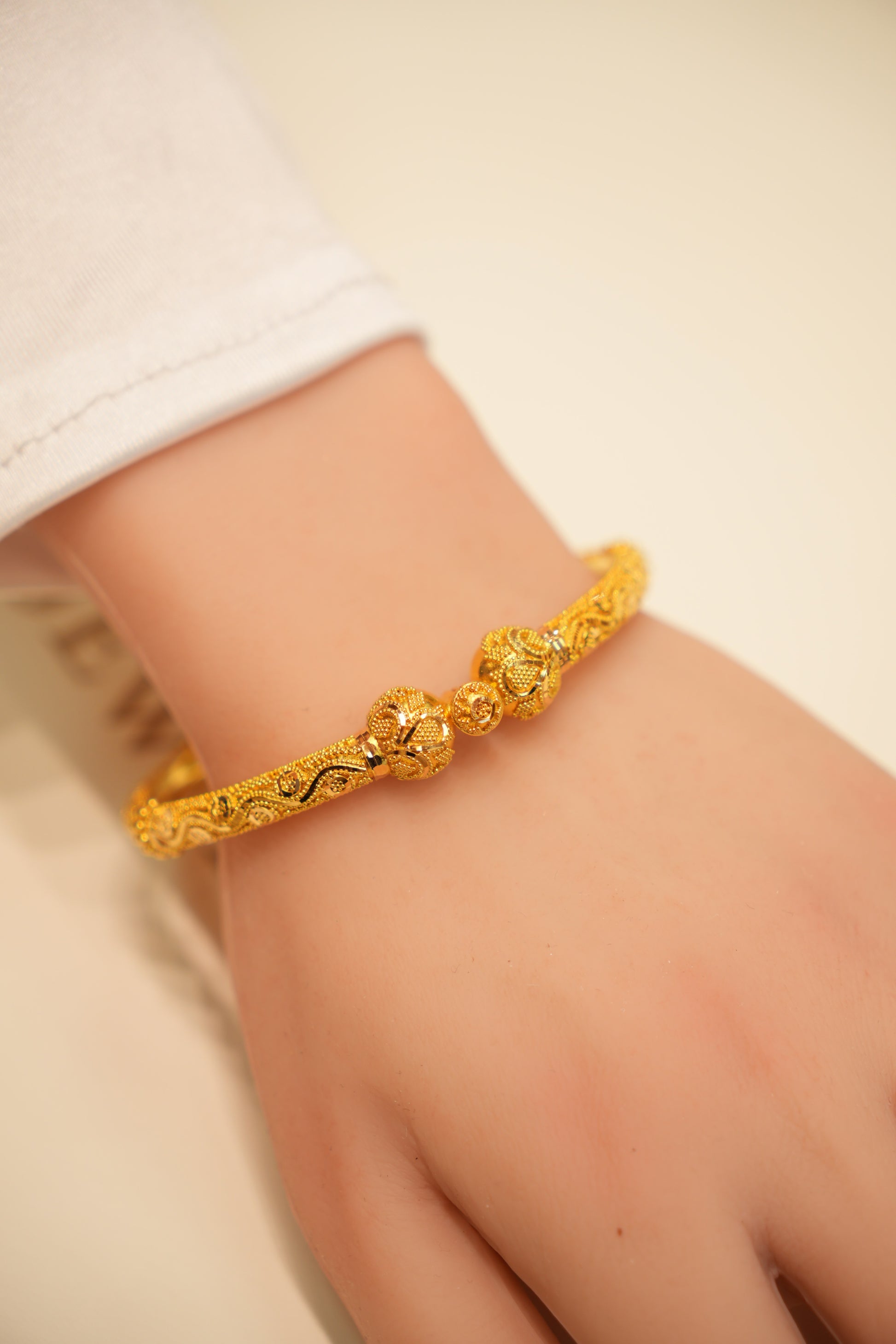 Gold bracelet on a person's wrist with a plain background