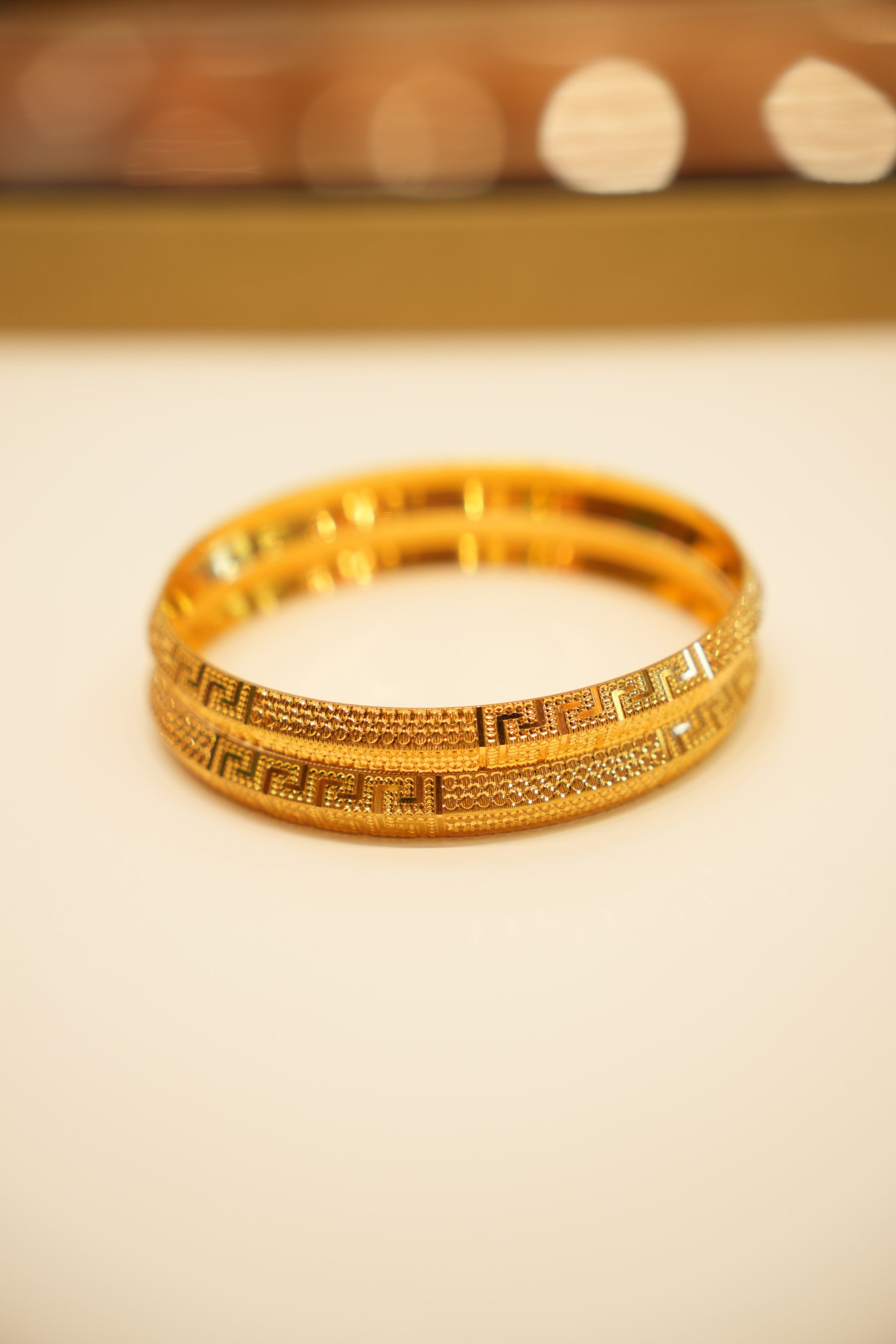 Gold bracelet with intricate design on a beige background