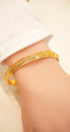 Gold bracelet on a person's wrist with a plain background