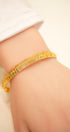 Gold bracelet on a wrist with a blurred background