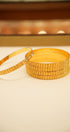 Stack of gold bangles on a beige surface with a blurred background