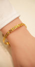 Gold bracelet on a wrist with a neutral background
