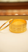 Stack of gold bangles on a light surface with a blurred background