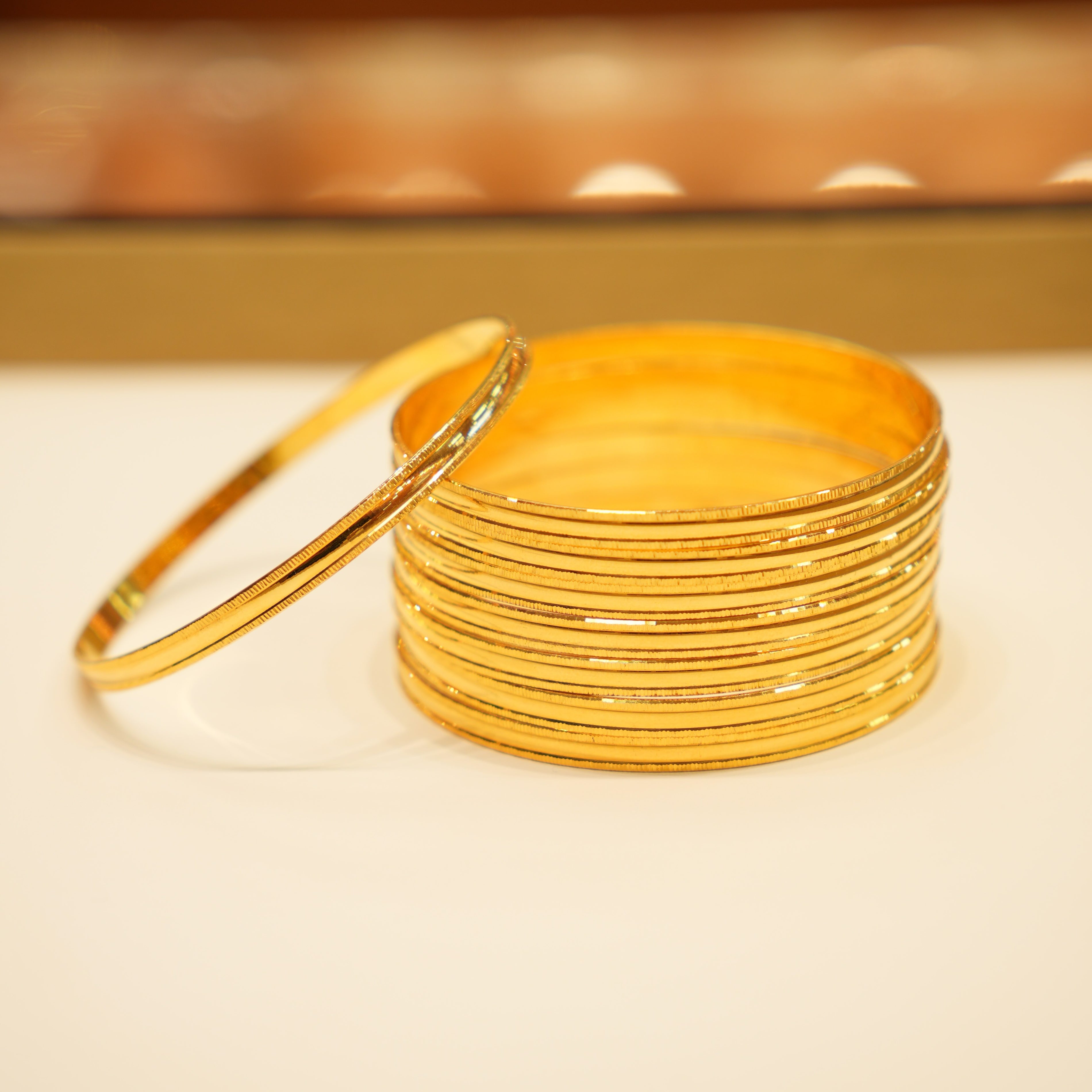 Stack of gold bangles on a light surface with a blurred background