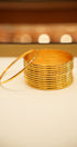 Stack of gold bangles on a white surface with a blurred background