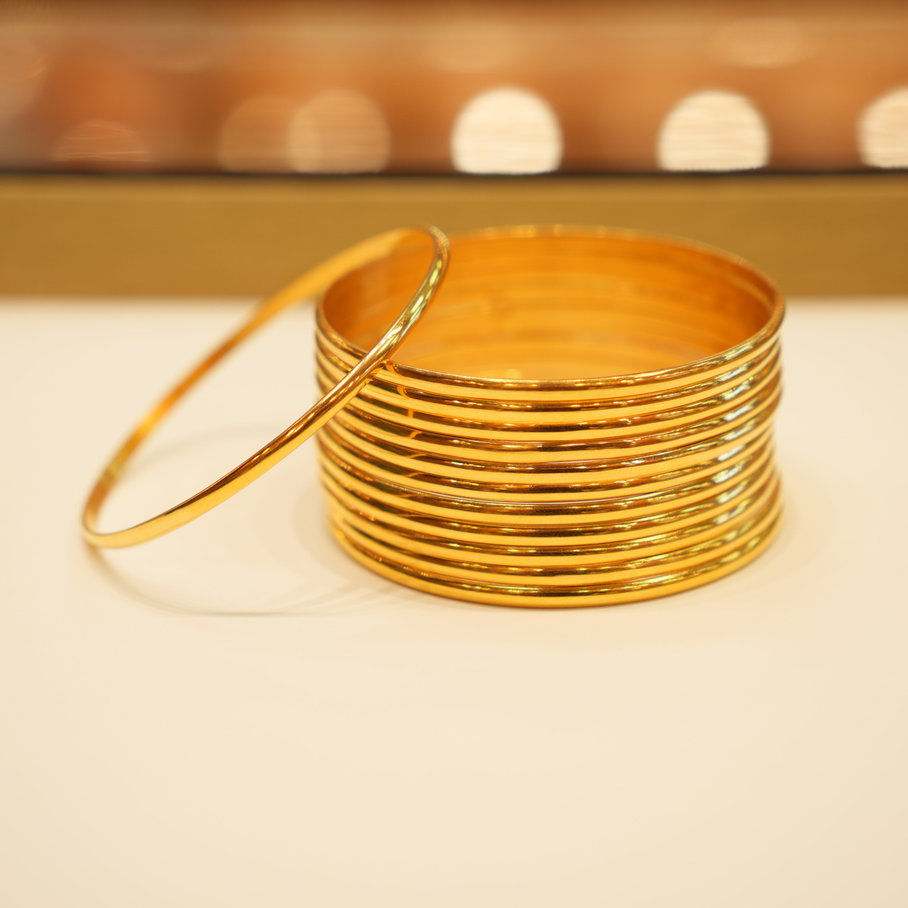 Stack of gold bangles on a white surface with a blurred background