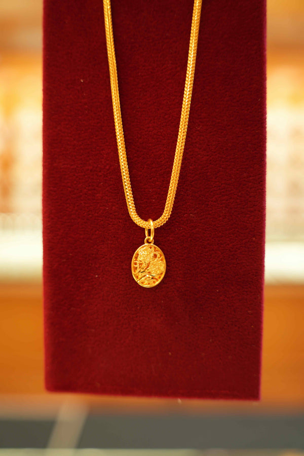 Gold necklace with a pendant on a red cushion