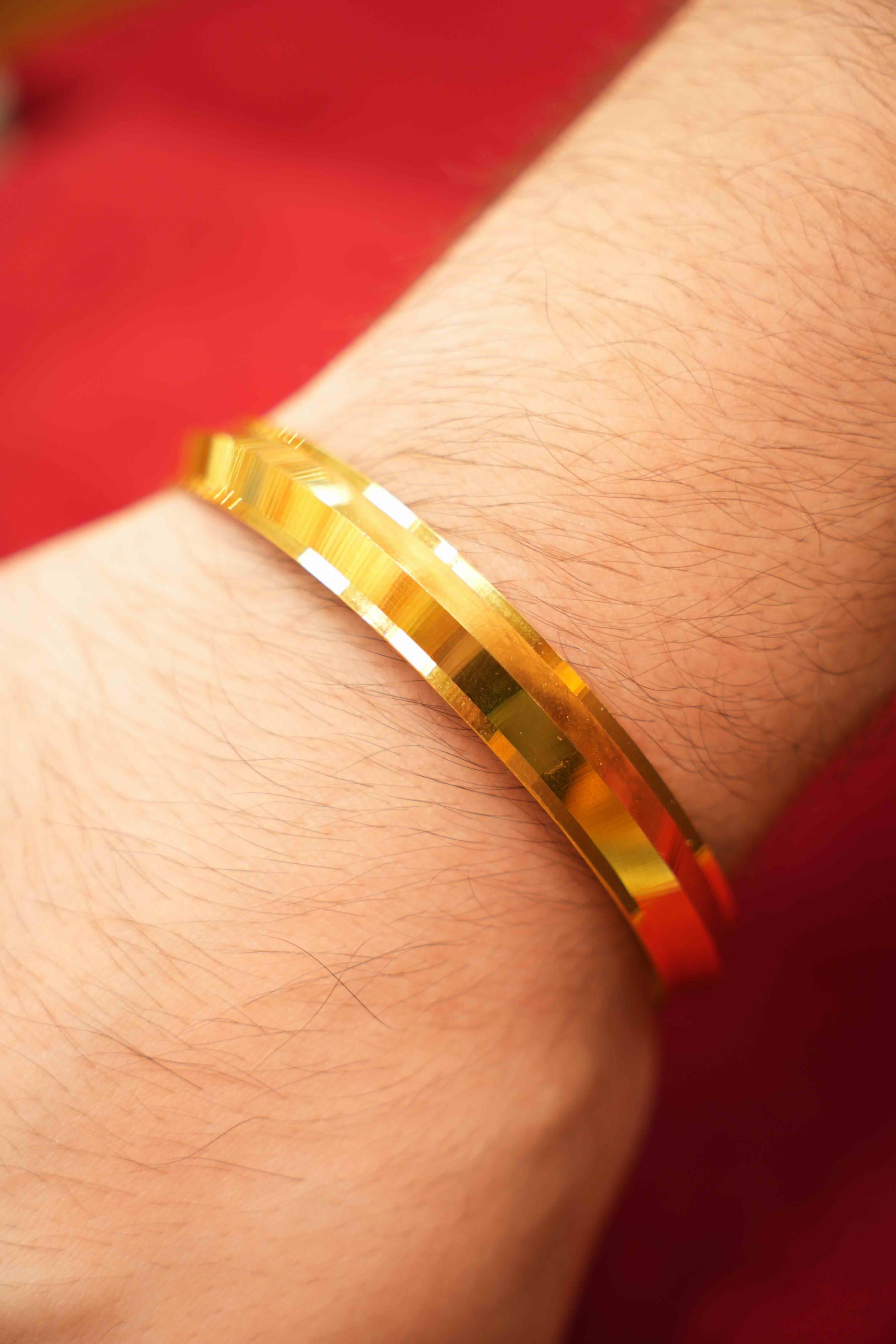 Gold bracelet on a wrist with a red background