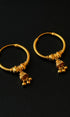 Pair of gold hoop earrings with small dangling charms on a black background