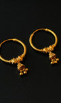 Pair of gold hoop earrings with small dangling charms on a black background