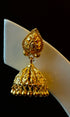 Gold jhumka earring on a white stand with a black background
