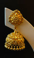 Gold earrings on a white stand against a black background
