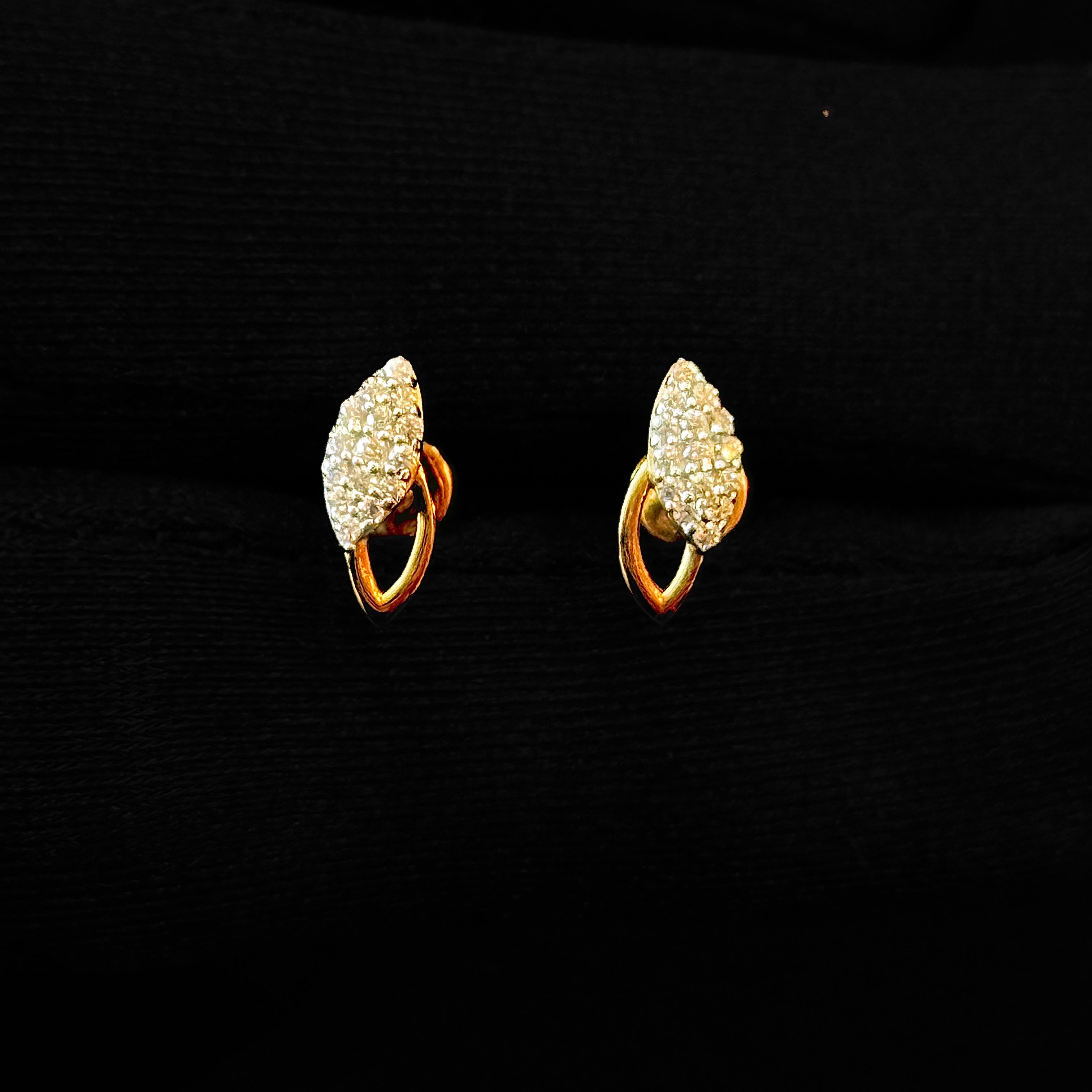 Pair of gold earrings with clear gemstones on a black background