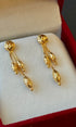 Gold earrings on a soft white cushion inside a red jewelry box