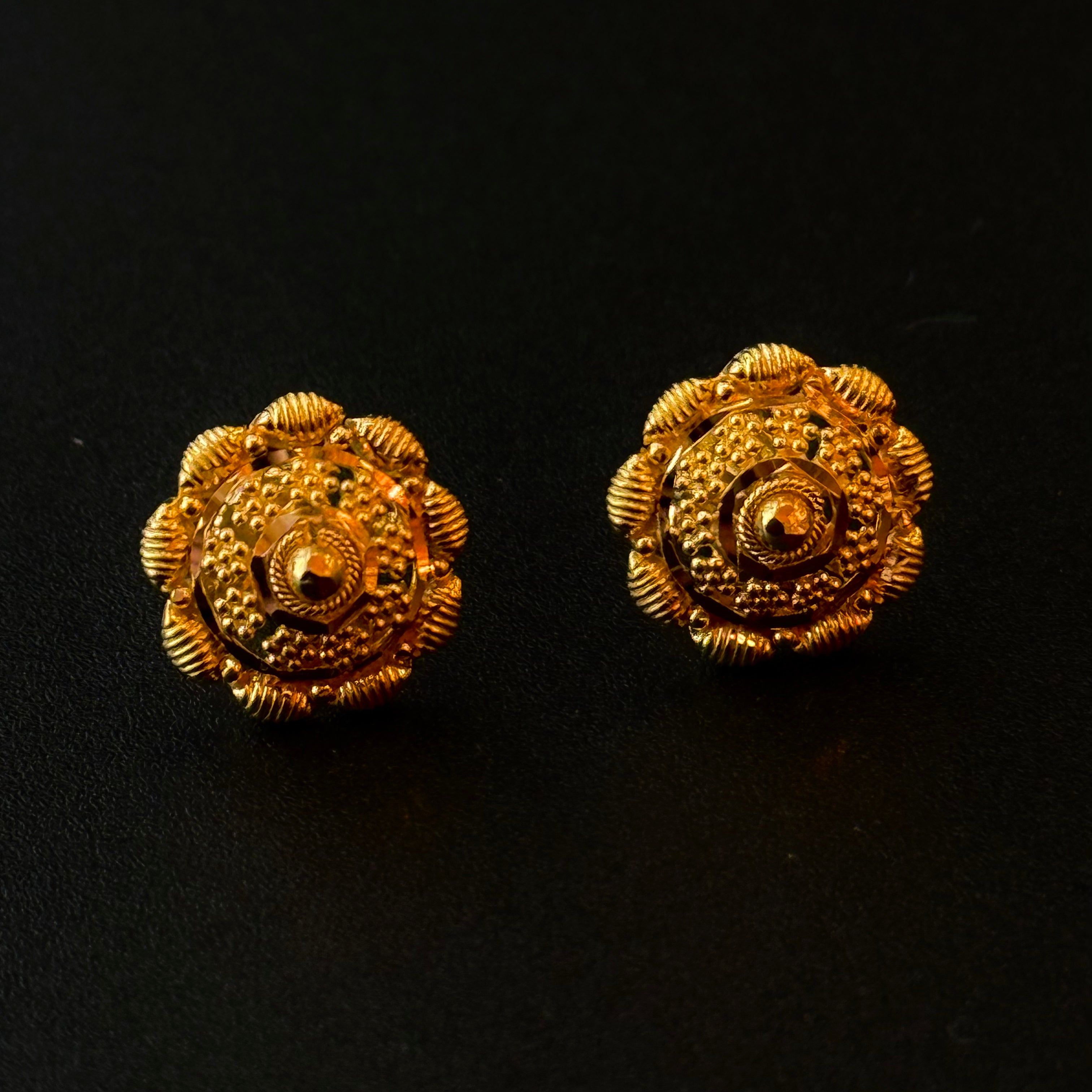 Pair of gold floral earrings on a black background