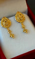 Gold earrings on a white cushion with a red border