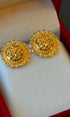 Pair of gold earrings on a soft white surface with a red border