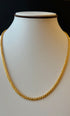 Gold chain necklace on a mannequin with a black background