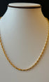 Gold chain necklace on a mannequin with a black background