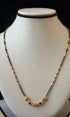 Necklace with black and gold beads on a mannequin bust against a black background